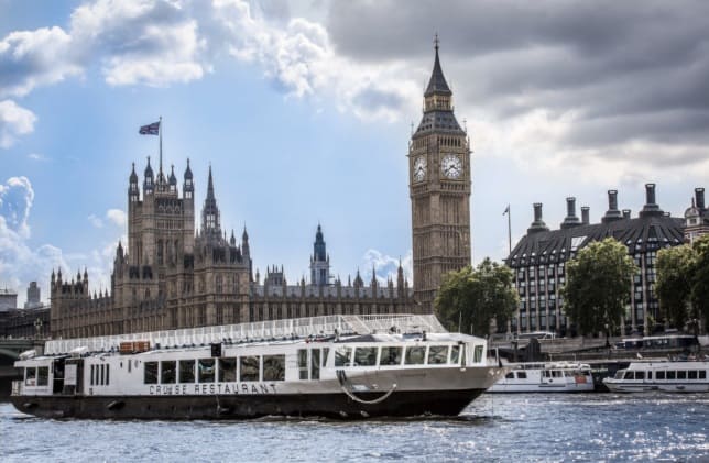 Thames sightseeing cruise boat passing the Houses of Parliament, fitted with an EasyGuide GPS multi-language audio commentary system