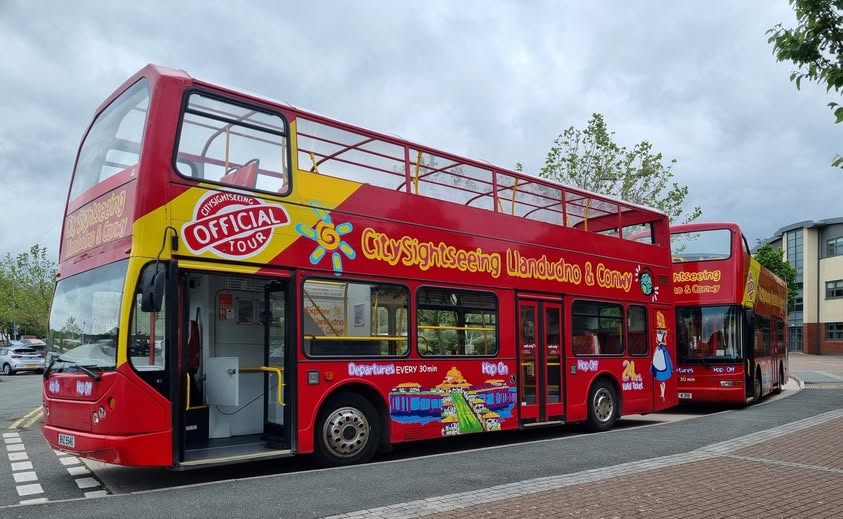 Red City Sightseeing open-top double-deckers operating the Llandudno and Conwy tour route, fitted with EasyGuide GPS multi-language audio commentary