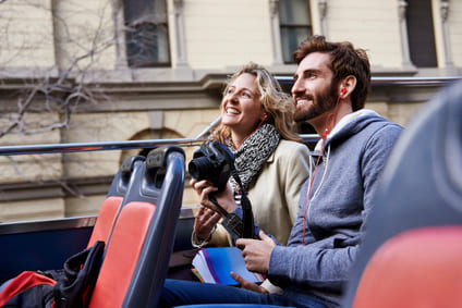 Sightseeing passengers enjoying an open-top city tour with EasyGuide multi-language audio commentary delivered through at-seat headsets