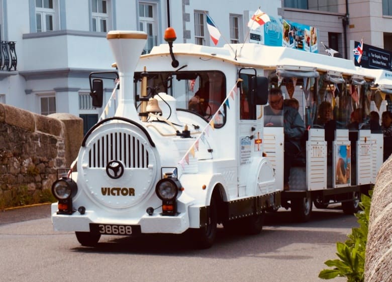 Tourist land train carrying passengers through a seaside town, with EasyGuide GPS commentary triggered automatically at points of interest along the route