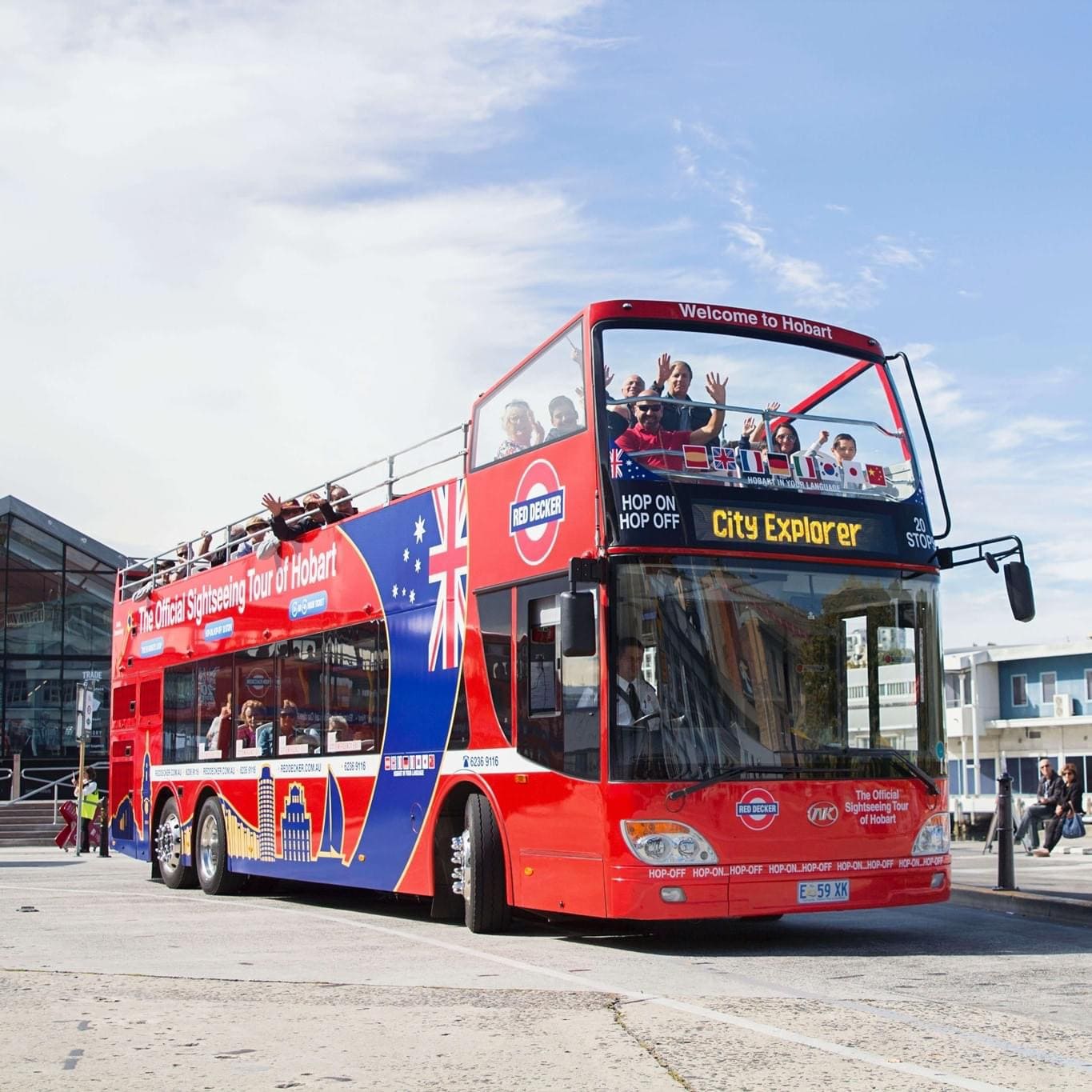 Red Decker open-top double-decker on the official sightseeing tour of Hobart, Tasmania, with passengers enjoying the journey from the upper deck - fitted with EasyGuide GPS multi-language audio commentary